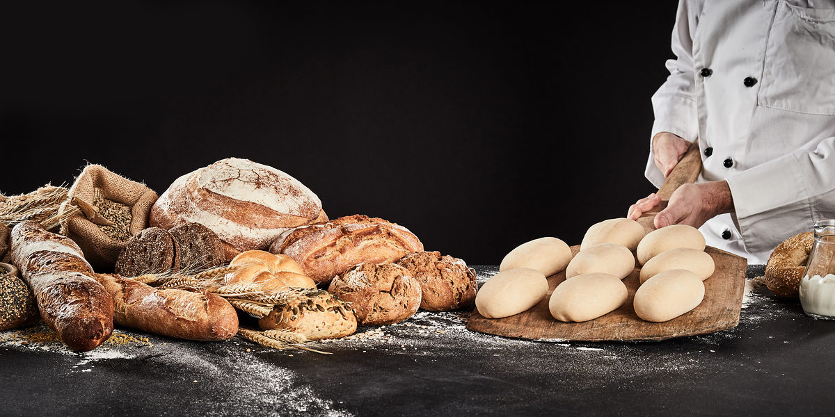 Baker holding a wooden paddle with formed dough ready to bake loaves of speciality bread displayed alongside in banner format Schlagwort(e): accompaniment, baker, bakery, baking, bread, food, gourmet, loaf, preparation, production, roll, speciality, carbohydrate, cereal, wheat, grain, chef, dough, holding, paddle, raw, ready, wooden, bagels, display, prepare, preparing, copy space, copy-space, copyspace, advertising, craft, bake, bakehouse, bakers, shop, whole, wholegrain, wholemeal, background, black, dark, banner, header, panorama, accompaniment, baker, bakery, baking, bread, food, gourmet, loaf, preparation, production, roll, speciality, carbohydrate, cereal, wheat, grain, chef, dough, holding, paddle, raw, ready, wooden, bagels, display, prepare, preparing, copy space, copy-space, copyspace, advertising, craft, bake, bakehouse, bakers, shop, whole, wholegrain, wholemeal, background, black, dark, banner, header, panorama