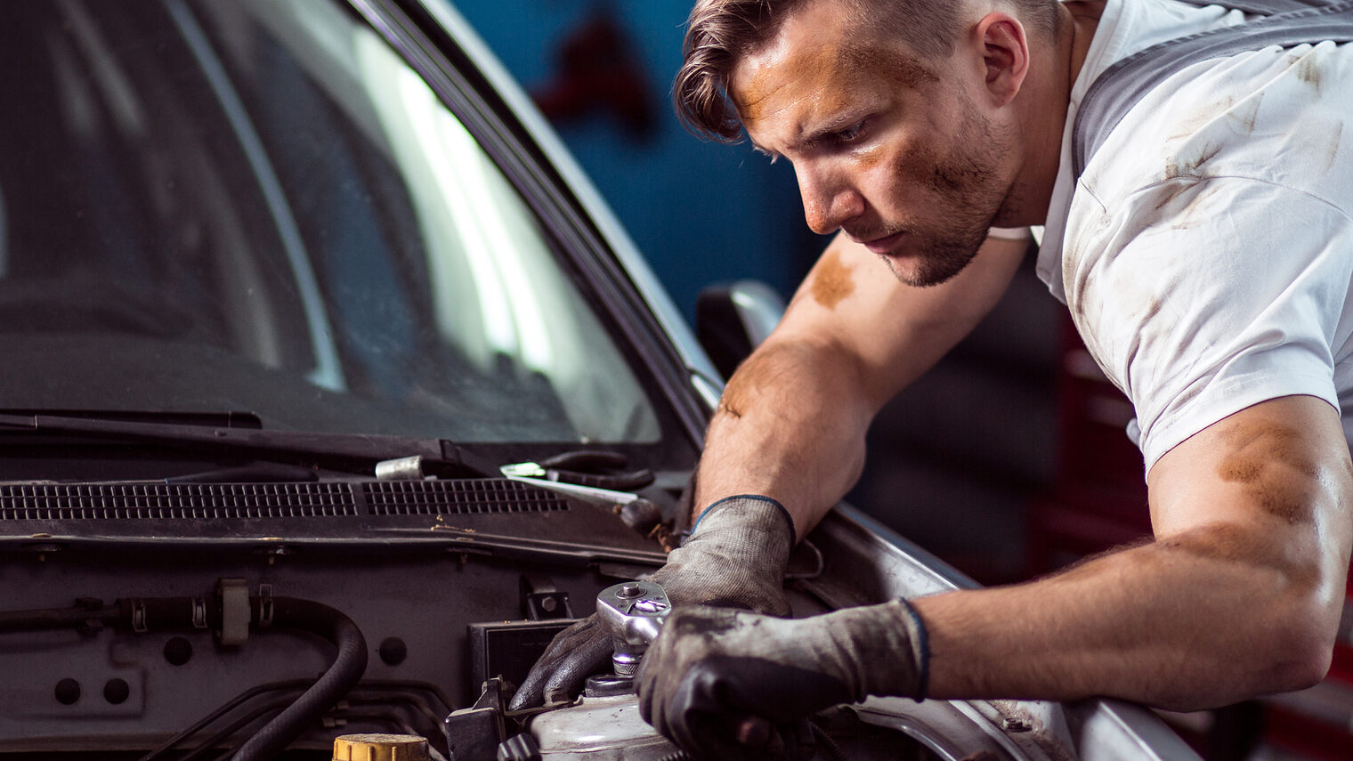 Young auto mechanic working in car repair shop Schlagwort(e): car, mechanic, repair, auto, shop, working, man, engine, motor, technician, fix, automotive, garage, panorama, automobile, repairing, male, vehicle, work, service, station, fixing, job, workshop, bonnet, change, engineer, servicing, equipment, mechanical, worker, technology, tool, key, professional, dirty, control, caucasian, gloves, profession