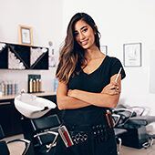Female hairdresser in salon holding scissors in hand. Smiling young hairdresser standing in salon. Schlagwort(e): arms crossed, barber shop, beautician, beauty, beauty salon, business, dresser, equipment, expertise, fashion, female, hair, hair salon, hairdresser, hairstylist, holding, indoors, looking, mirror, occupation, parlor, portrait, professional, salon, scissors, smiling, staff, standing, studio, stylist, tool, woman, young