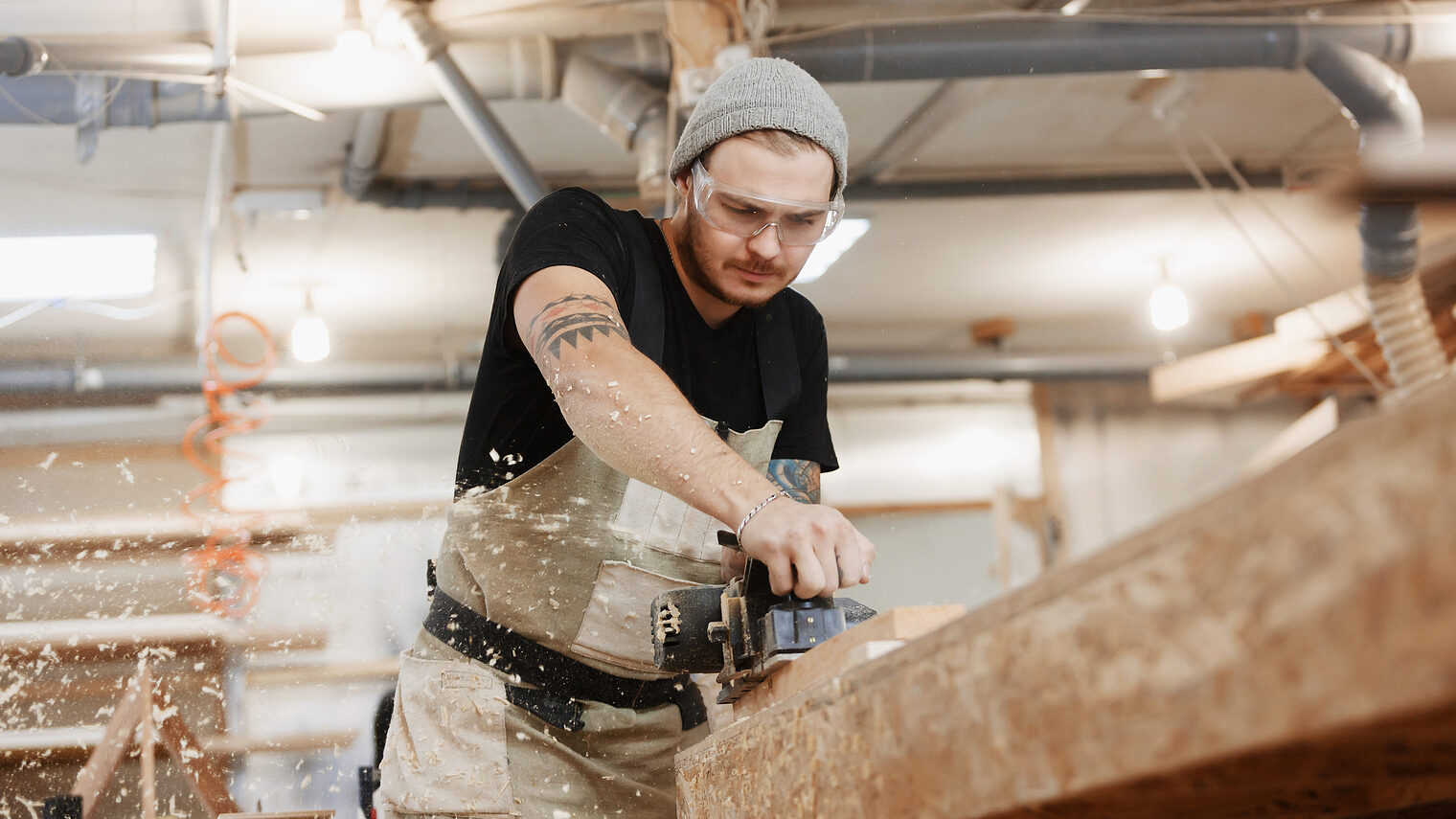 Carpenter working with electric planer on wooden plank in workshop. Hands and planer close up. Schlagwort(e): people, planer, carpenter, workshop, furniture, work, wooden, woodworker, woodworking, manufacture, wood, maker, diy, woodshop, machine, electric, shop, woodwork, cabinet, industry, timber, carpentry, caucasian, craft, craftsman, equipment, handmade, hand, holding, improvement, instrument, lumber, men, occupation, one, person, plane, planks, powertool, profession, professional, rasping, sawdust, scobs, tools, workbench, worker, workman, people, planer, carpenter, workshop, furniture, work, wooden, woodworker, woodworking, manufacture, wood, maker, diy, woodshop, machine, electric, shop, woodwork, cabinet, industry, timber, carpentry, caucasian, craft, craftsman, equipment, handmade, hand, holding, improvement, instrument, lumber, men, occupation, one, person, plane, planks, powertool, profession, professional, rasping, sawdust, scobs, tools, workbench, worker, workman