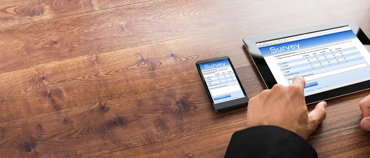 Close-up Of A Businessman Filling Survey Form Online On Digital Tablet And Cellphone Schlagwort(e): survey, online, feedback, form, quality, control, fill, research, questionnaire, person, filling, people, business, poll, businessman, checklist, tablet, vote, card, mobile