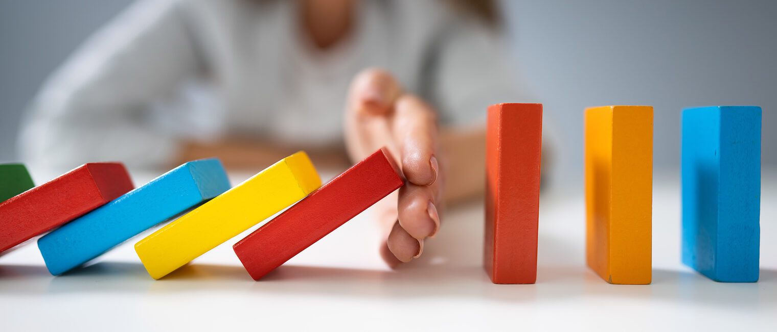 High Angle View Of A Businessperson Stopping Colorful Dominoes From Falling On Desk Schlagwort(e): fall, prevention, falling, falls, stop, business, one, failure, risk, hand, stopping, success, blocks, domino, colorful, businessperson, solutions, intervention, preventing, game